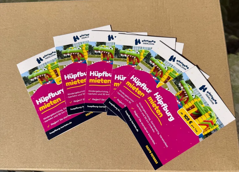 Mehrere gedruckte Flyer aufgefächert, Titelseite mit Hüpfburg-Motiv